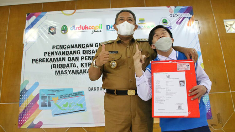 Plt Walikota Bandung Yana Mulyana saat memberikan dokumen kependudukan kepada penyandang disabilitas.